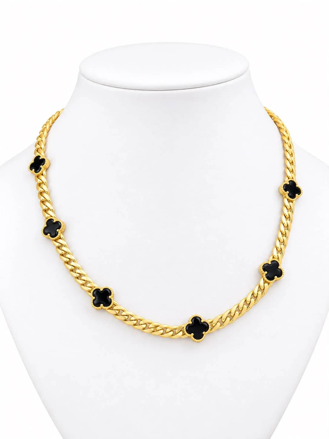 Gold Cuban chain with black onyx clover stations on a white bust